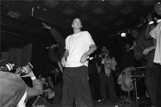 NEW YORK - MARCH 1999:  Rapper Eminem, seated, and unidentified rappers and DJs on turntables in background, perform at Tramps in March 1999 in New York City, New York. (Photo by Catherine McGann/Getty Images)