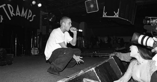 NEW YORK - MARCH 1999:  Rapper Eminem, seated, and unidentified rappers and DJs on turntables in background, perform at Tramps in March 1999 in New York City, New York. (Photo by Catherine McGann/Getty Images)