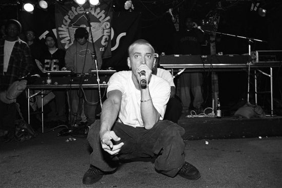 NEW YORK - MARCH 1999:  Rapper Eminem, seated, and unidentified rappers and DJs on turntables in background, perform at Tramps in March 1999 in New York City, New York. (Photo by Catherine McGann/Getty Images)