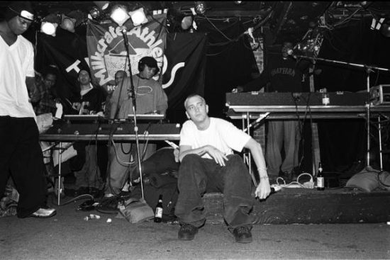 NEW YORK - MARCH 1999:  Rapper Eminem, seated, and unidentified rappers and DJs on turntables in background, perform at Tramps in March 1999 in New York City, New York. (Photo by Catherine McGann/Getty Images)